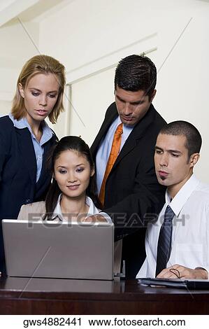 Two businessmen and two businesswomen in front of a laptop View Large Photo Image Stock Image - Two businessmen and two businesswomen in front of a laptop. Fotosearch