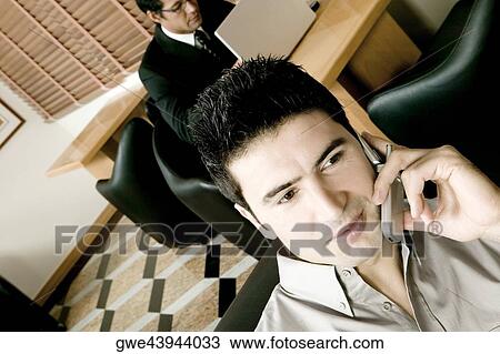 Two young businessmen working in an office View Large Photo Image Stock Image - Two young businessmen working in an office. Fotosearch
