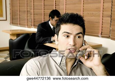 Two young businessmen working in an office View Large Photo Image Stock Photograph - Two young businessmen working in an office. Fotosearch