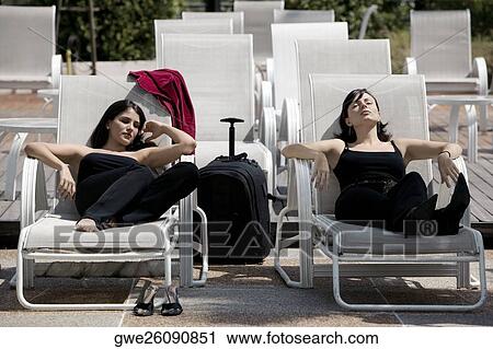 Two young women relaxing on lounge chairs View Large Photo Image Stock Image - Two young women relaxing on lounge chairs. Fotosearch