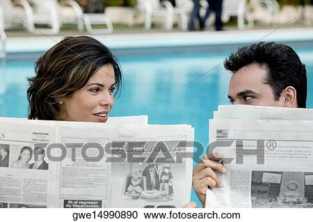 Young couple holding newspapers looking at each other View Large Photo Image Stock Image - Young couple holding newspapers looking at each other. Fotosearch