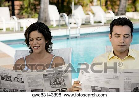 Young couple reading newspaper View Large Photo Image Stock Photo - Young couple reading newspaper. Fotosearch