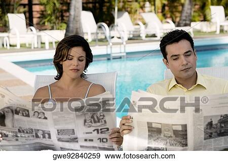 Young couple reading newspaper View Large Photo Image Stock Photo - Young couple reading newspaper. Fotosearch