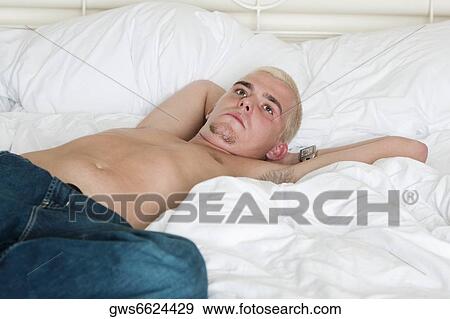 Young man lying on the bed looking up View Large Photo Image Stock Photo - Young man lying on the bed looking up. Fotosearch