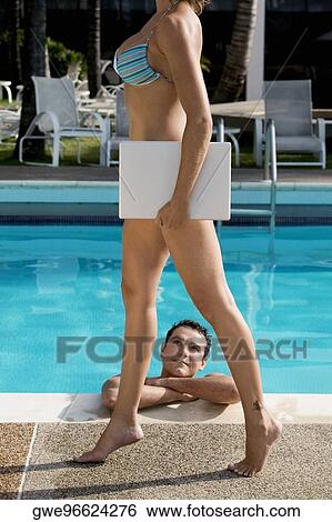 Young woman carrying a laptop with a young man looking at her View Large Photo Image Stock Photograph - Young woman carrying a laptop with a young man looking at her. Fotosearch
