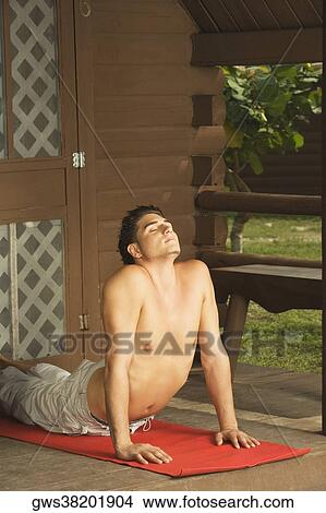 Picture - Bare chested young man performing the cobra pose. Fotosearch