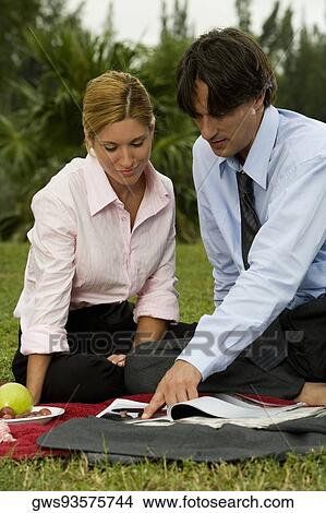 Businessman and a businesswoman reading a magazine in the park View Large Photo Image Picture - Businessman and a businesswoman reading a magazine in the park. Fotosearch