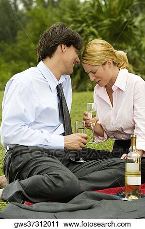 Businessman and a businesswoman sitting in the park holding champagne flutes View Large Photo Image Stock Image - Businessman and a businesswoman sitting in the park holding champagne flutes. Fotosearch