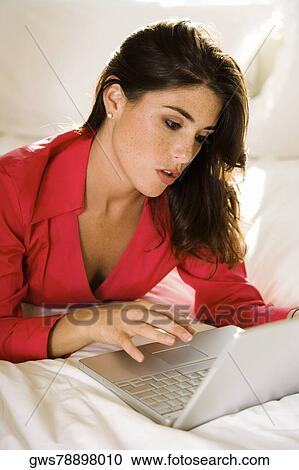 Businesswoman lying on the bed using a laptop View Large Photo Image Stock Image - Businesswoman lying on the bed using a laptop. Fotosearch