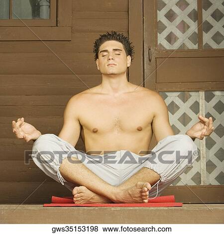 Stock Photo - Close-up of a bare chested young man sitting in a lotus position and meditating. Fotosearch