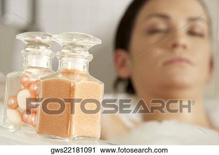 Close-up of a bath powder and bath pearls in glass bottles with a young woman in the bathtub in the background View Large Photo Image Stock Image - Close-up of a bath powder and bath pearls in glass bottles with a young woman in the bathtub in the background. Fotosearch
