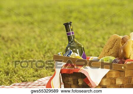 Stock Photo - Close-up of a bottle with fruit and buns in a basket. Fotosearch