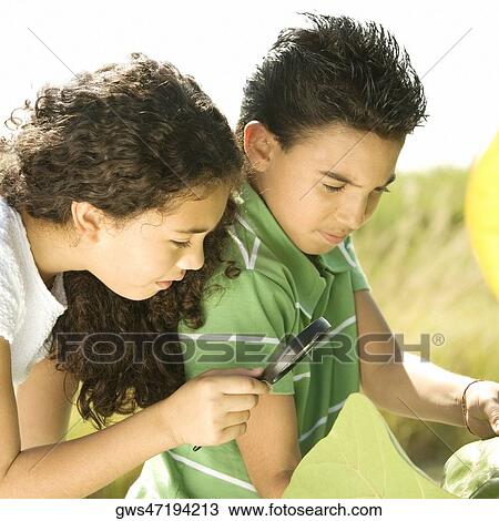 Stock Image - Close-up of a boy and a girl looking through a magnifying glass. Fotosearch