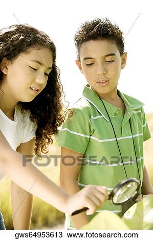 Close-up of a boy and a girl looking through a magnifying glass View Large Photo Image Stock Image - Close-up of a boy and a girl looking through a magnifying glass. Fotosearch