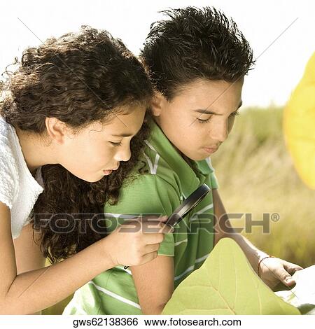 Stock Photograph - Close-up of a boy and a girl looking through a magnifying glass. Fotosearch