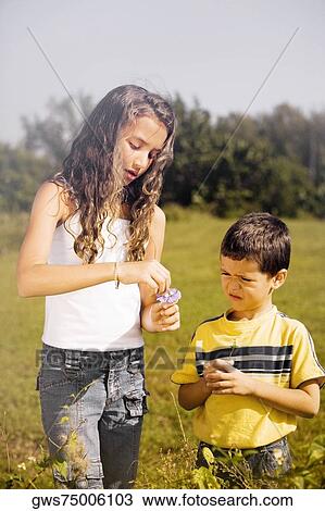 Stock Image - Close-up of a boy and his sister standing in the park. Fotosearch