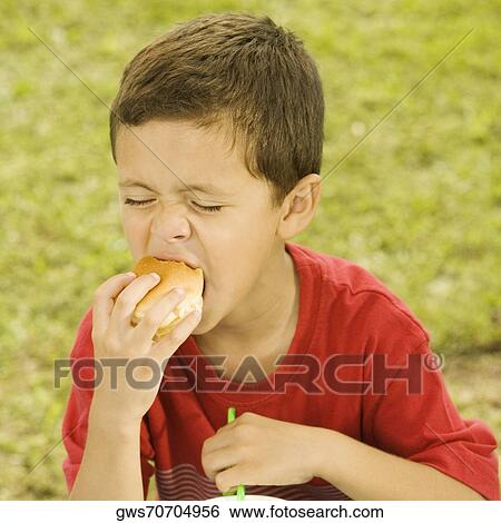 Close-up of a boy eating a burger View Large Photo Image Stock Photograph - Close-up of a boy eating a burger. Fotosearch