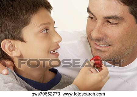 Close-up of a boy feeding his father a strawberry View Large Photo Image Stock Image - Close-up of a boy feeding his father a strawberry. Fotosearch