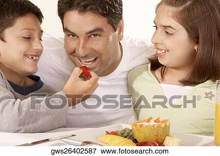 Close-up of a boy feeding his father a strawberry View Large Photo Image Stock Photo - Close-up of a boy feeding his father a strawberry. Fotosearch