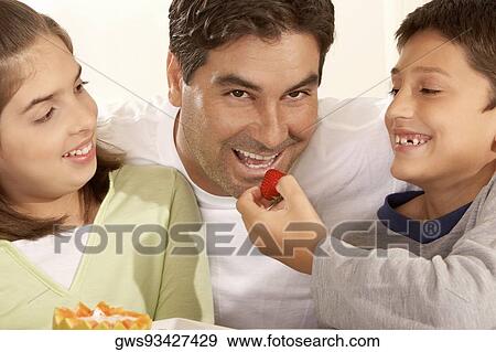 Close-up of a boy feeding his father a strawberry View Large Photo Image Stock Photo - Close-up of a boy feeding his father a strawberry. Fotosearch