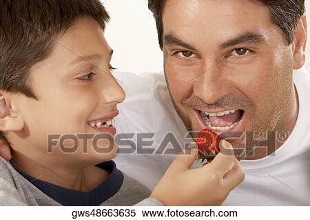 Close-up of a boy feeding his father a strawberry View Large Photo Image Stock Photography - Close-up of a boy feeding his father a strawberry. Fotosearch