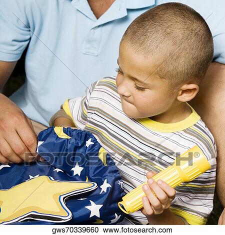 Stock Image - Close-up of a boy holding a flashlight with his father. Fotosearch