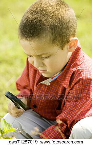 Close-up of a boy looking at a plant through a magnifying glass View Large Photo Image Stock Photo - Close-up of a boy looking at a plant through a magnifying glass. Fotosearch