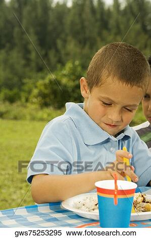 Close-up of a boy sitting at the table looking down View Large Photo Image Stock Photography - Close-up of a boy sitting at the table looking down. Fotosearch