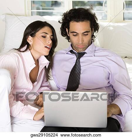 Close-up of a businessman and a businesswoman sitting on the bed using a laptop View Large Photo Image Picture - Close-up of a businessman and a businesswoman sitting on the bed using a laptop. Fotosearch