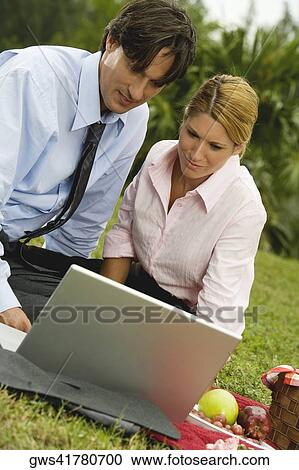 Close-up of a businessman and a businesswoman working on a laptop in the park View Large Photo Image Stock Image - Close-up of a businessman and a businesswoman working on a laptop in the park. Fotosearch