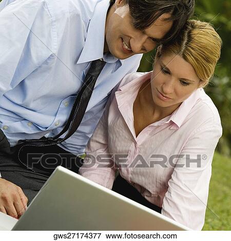 Close-up of a businessman and a businesswoman working on a laptop in the park View Large Photo Image Stock Photo - Close-up of a businessman and a businesswoman working on a laptop in the park. Fotosearch