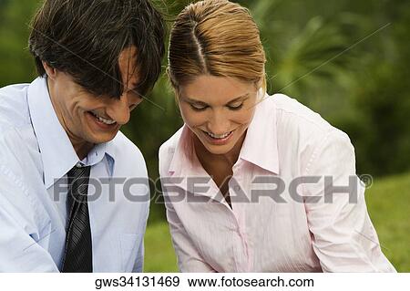 Stock Photo - Close-up of a businessman and a businesswoman smiling in the park. Fotosearch
