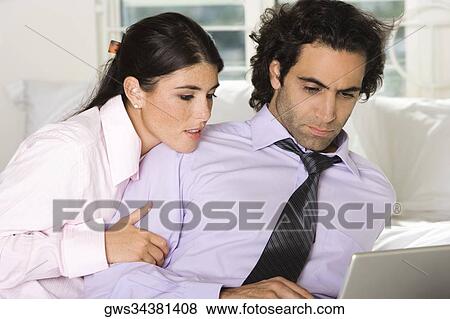 Close-up of a businessman and a businesswoman sitting on the bed using a laptop View Large Photo Image Stock Photo - Close-up of a businessman and a businesswoman sitting on the bed using a laptop. Fotosearch