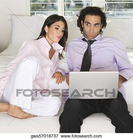 Close-up of a businessman and a businesswoman sitting on the bed using a laptop View Large Photo Image Stock Photo - Close-up of a businessman and a businesswoman sitting on the bed using a laptop. Fotosearch