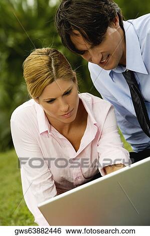 Close-up of a businessman and a businesswoman working on a laptop in the park View Large Photo Image Stock Photograph - Close-up of a businessman and a businesswoman working on a laptop in the park. Fotosearch