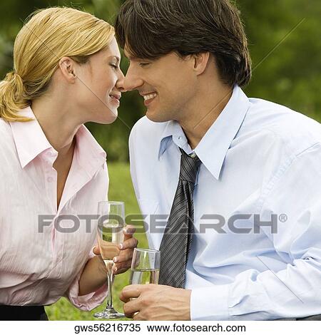 Close-up of a businessman and a businesswoman sitting in the park holding champagne flutes View Large Photo Image Stock Photography - Close-up of a businessman and a businesswoman sitting in the park holding champagne flutes. Fotosearch