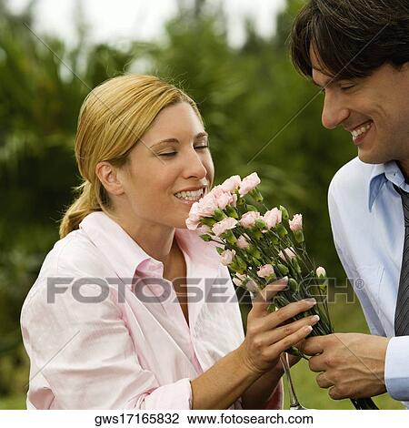 Close-up of a businessman holding a bunch of flowers with a businesswoman smelling them View Large Photo Image Stock Image - Close-up of a businessman holding a bunch of flowers with a businesswoman smelling them. Fotosearch