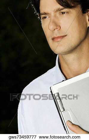 Stock Photo - Close-up of a businessman holding a laptop. Fotosearch