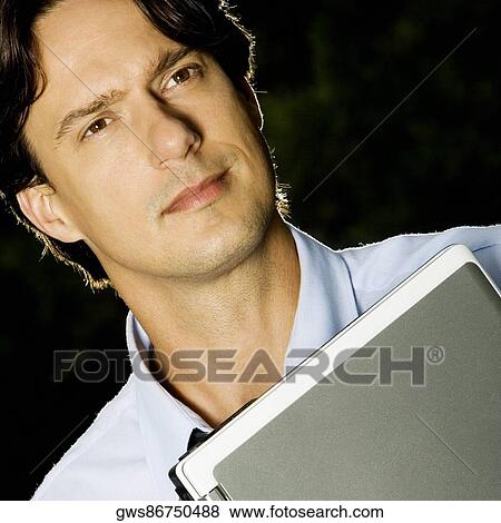 Stock Photo - Close-up of a businessman holding a laptop. Fotosearch