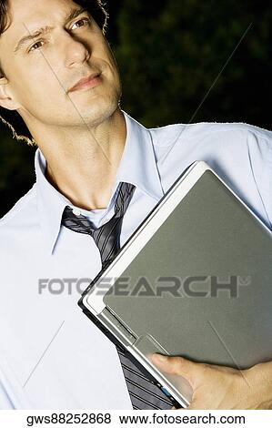 Close-up of a businessman holding a laptop View Large Photo Image Stock Photo - Close-up of a businessman holding a laptop. Fotosearch