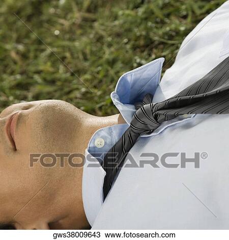 Close-up of a businessman lying on the grass View Large Photo Image Stock Image - Close-up of a businessman lying on the grass. Fotosearch