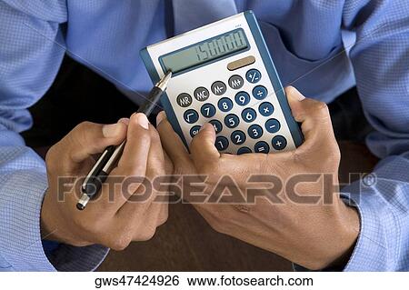Stock Photograph - Close-up of a businessman's hand holding a calculator. Fotosearch