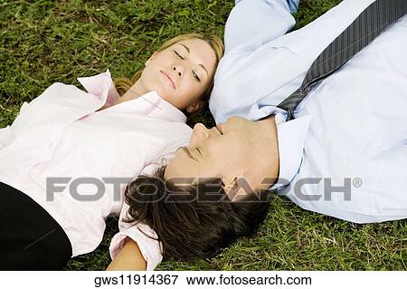 Stock Photo - Close-up of a businesswoman and a businessman lying on the grass. Fotosearch