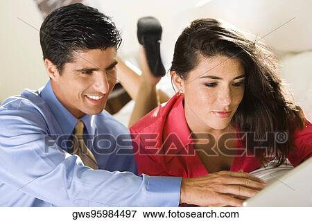 Close-up of a businesswoman and a businessman using a laptop View Large Photo Image Stock Photo - Close-up of a businesswoman and a businessman using a laptop. Fotosearch