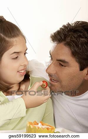 Close-up of a girl feeding her father a strawberry View Large Photo Image Stock Image - Close-up of a girl feeding her father a strawberry. Fotosearch