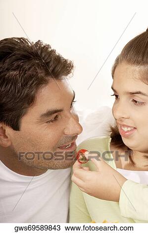 Close-up of a girl feeding her father a strawberry View Large Photo Image Stock Image - Close-up of a girl feeding her father a strawberry. Fotosearch