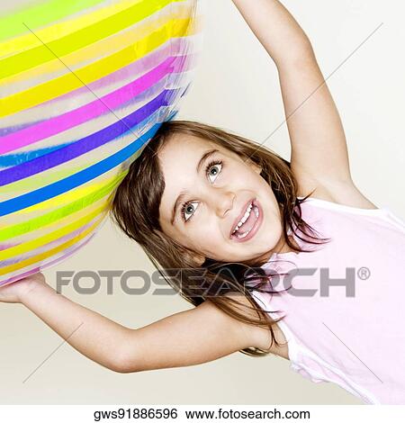 Close-up of a girl holding a ball over her head View Large Photo Image Stock Photograph - Close-up of a girl holding a ball over her head. Fotosearch