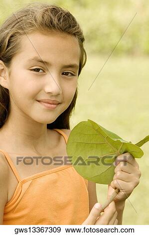 Stock Photo - Close-up of a girl holding a leaf smiling. Fotosearch
