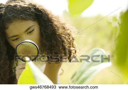 Close-up of a girl looking through a magnifying glass View Large Photo Image Stock Image - Close-up of a girl looking through a magnifying glass. Fotosearch