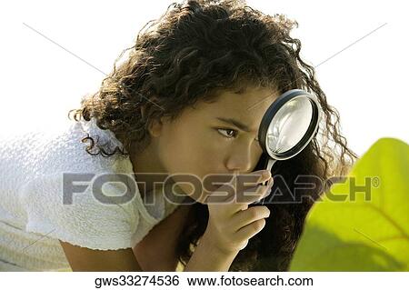 Close-up of a girl looking through a magnifying glass View Large Photo Image Stock Photograph - Close-up of a girl looking through a magnifying glass. Fotosearch